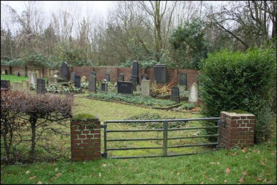 A low iron gate. In the background tombstones