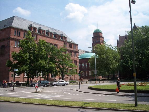 Auf dem Foto sieht man einen grün bepflanzten Platz und das Hauptgebäude der Albert-Ludwigs-Universität.