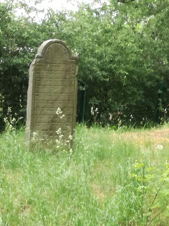 Photograph of the front of a gravestone located on the left side of the path.