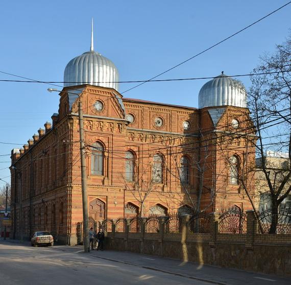 The view of the red-orange building of the synagogue with two silver domes, taken from the forecourt in front of the synagogue.