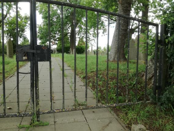 View through the closed entrance gate - view of gravestones on the right side