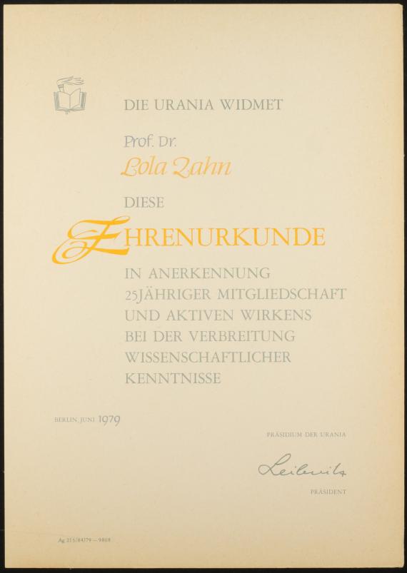 Eine blaue Mappe, die gold mit dem Text “Akademie der Wissenschaften der DDR” bedruckt ist; die Mappe enthält eine Urkunde, auf der mit großen Lettern Lola Zahn für ihre 25jährige Mitgliedschaft ausgezeichnet wird. 
