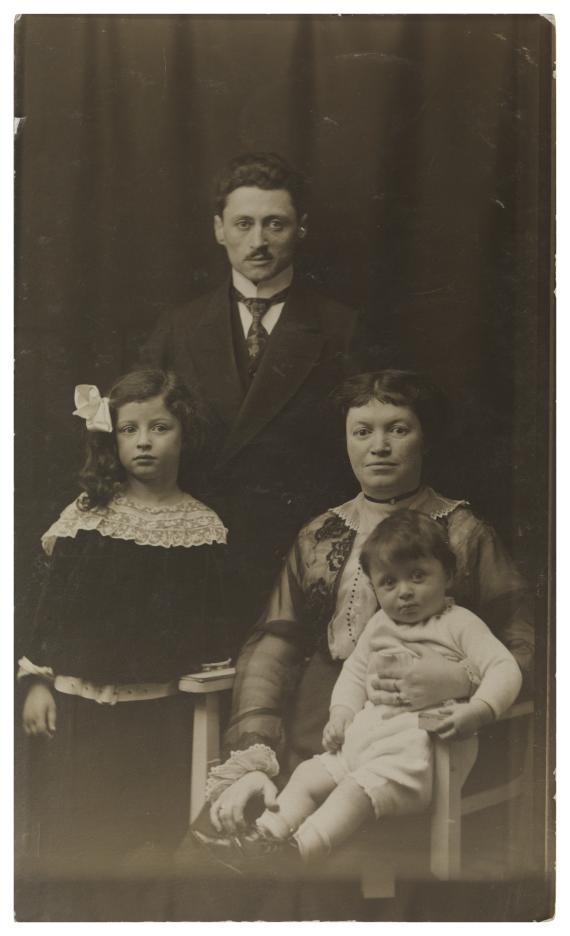 Fotografie in schwarz-weiß, auf welchem die Eltern Lazar und Malka Golodetz mit der etwa sechsjährigen Helene und dem jüngeren Victor in einem Foto-Atelier zu sehen sind. Der Vater steht hinter der ebenfalls stehenden Helene und der sitzenden Mutter, welche Victor auf dem Schoß sitzend hat. Alle vier sind vornehm gekleidet. Die Eltern gucken mit neutralem Blick in die Kamera, der Sohn lächelt leicht und Helene guckt leicht daneben. 