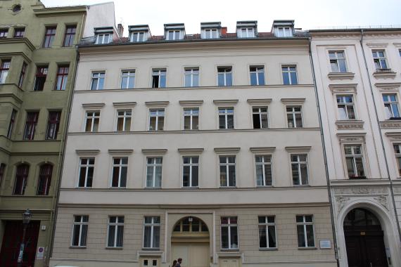 A five-storey residential building. The gate entrance is vaulted, next to it are two entrances to the basement.