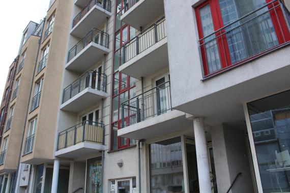 Two five-story apartment buildings. House number 10 painted white with red window frames, house number 11 painted beige with white window frames.