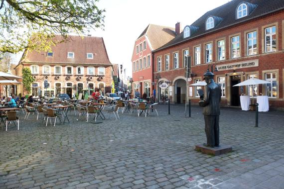 Marktplatz in der Stadt Telgte. Rechts im Bild eine dunkle Statue eines Mannes. 