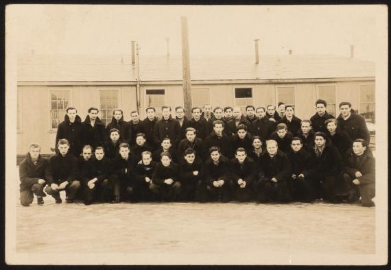 Gruppenfoto junger Internierter in Farnham, Kanada. Manche lächeln, manche nicht, alle tragen dicke Wintermäntel, es liegt Schnee.