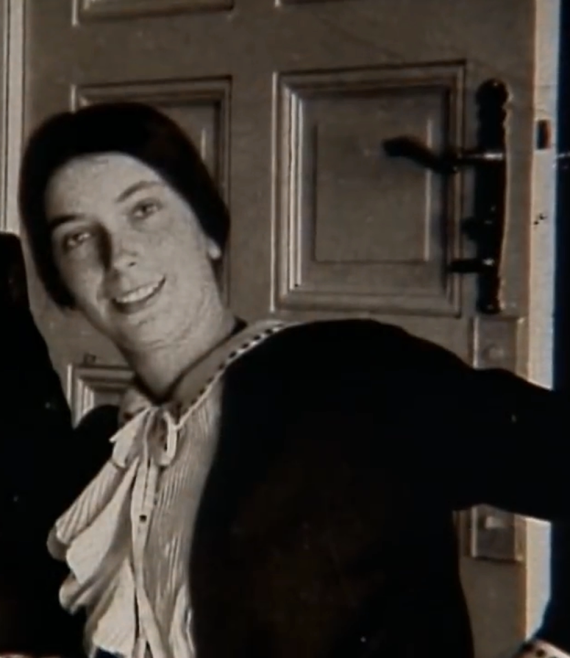 Charlotte Gossels, née Lewy, younger daughter of Lina and Isidor Lewy, in her parents' apartment in the VH 2nd floor. She stands in front of a room door and smiles at the viewer.