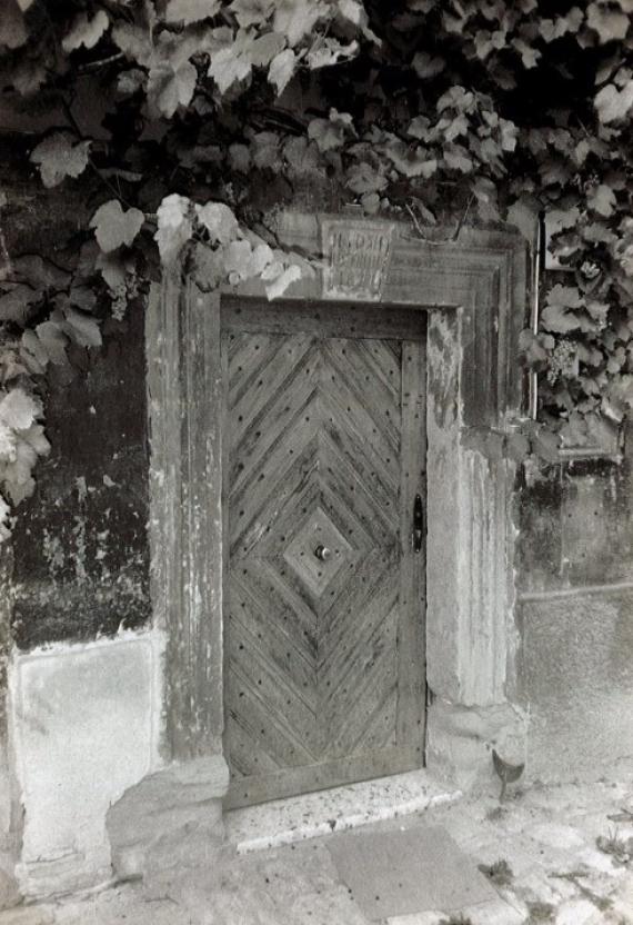 Front door of the building Hauptstr. 9 with keystone above the door and vines.