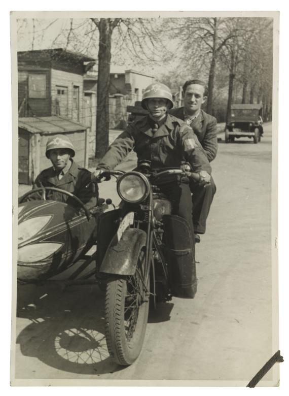 Three policemen of the DP camp on a motorcycle with a sidecar. Two wear steel helmets with a Star of David.