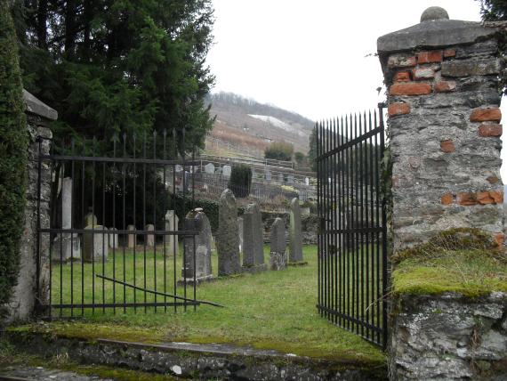 Eingangstor zum neuen jüdischen Friedhof, dahinter Rasenfläche mit Grabsteinen