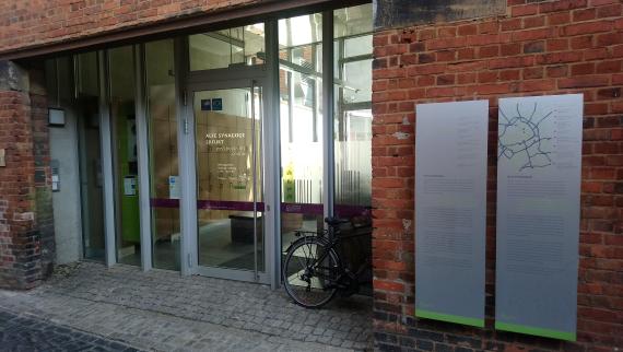 You can see a glazed entrance with a door between brick walls.