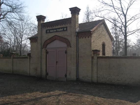 Links und rechts helle Backsteinmauer. Zwischen den Backsteinmauern befindet sich das Eingangsportal des jüdischen Friedhofs. 