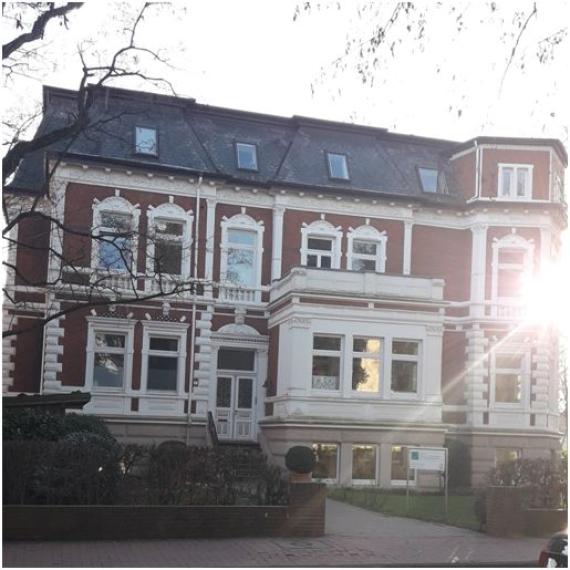 In der Nordstraße 2 steht eine rot-weiß getäfelte Stadtvilla im Barockstil mit einem weißen Vorbau mit Balkon. 