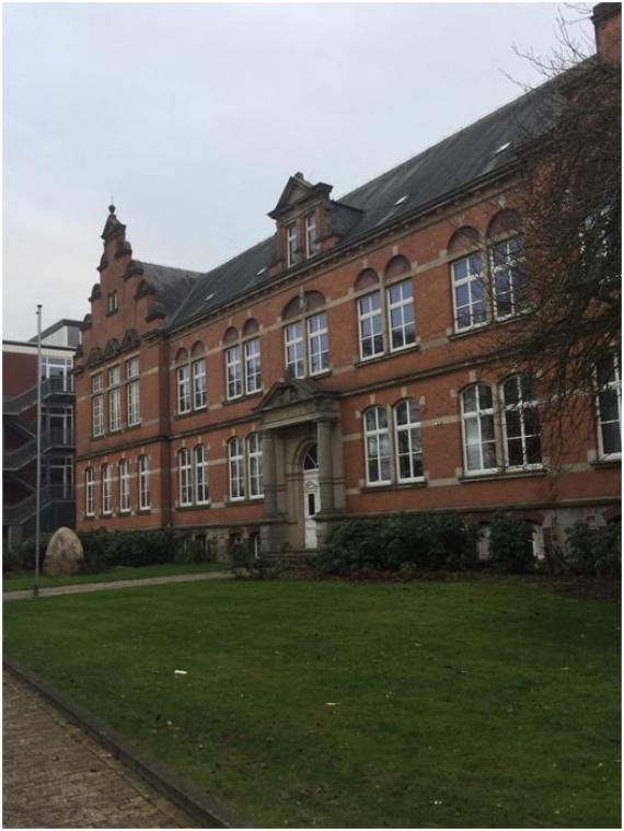 Photo of Mariengymnasium in Jever in 2019, showing a brick building with green space in the foreground.