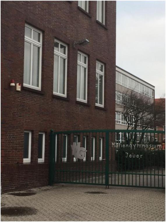 Current photograph of the school gate with logo. On the left you can see a part of the brick building and behind it the new extension.