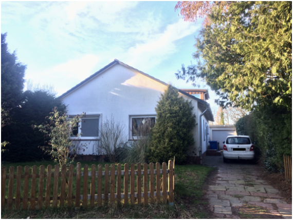 weißes Haus mit einem kleinen Anbau und einer Garage auf der rechten Seite des Hauses