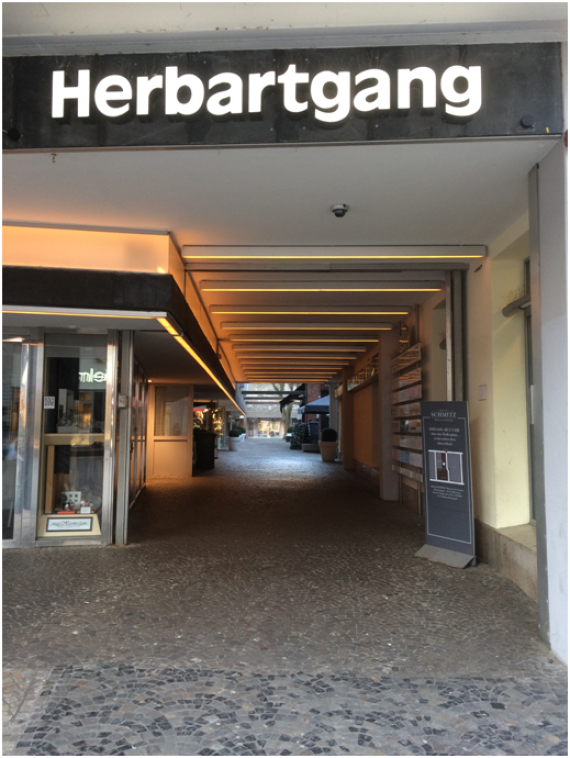 Gang in der Innenstadt von Oldenburg, an dem oben der Schriftzug „Herbartgang“ mit hell beleuchteten Buchstaben befestigt ist