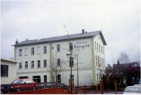 Color photograph of a three-story house with pointed roof. Under the roof is written in blue letters "Wäscherei Reingold".