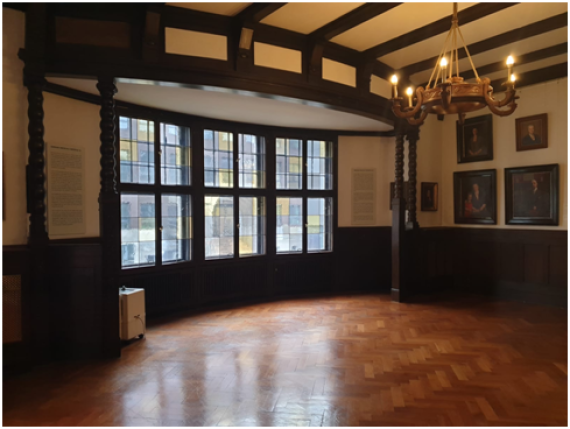 Interior of the villa with three large windows and parquet floor and a chandelier