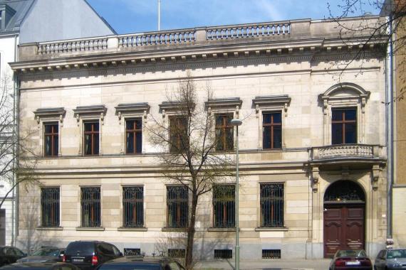 Das Bild zeigt die Fassade des bis heute erhaltenen Hauses. Es ist zweigeschossig und wurde von den Architekten Schmieden und Gropius im Stil des Neoklassizismus erbaut. 