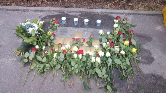 Stolpersteine, stones made of brass laid in the concrete sidewalk. The stones are inscribed with names and dates.