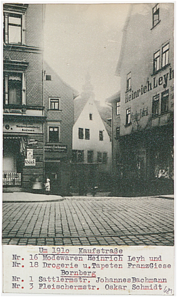 Die Kaufstraße um das Jahr 1910. Die Fotographie zeigt Häuser, die Straße sowie ein kleines Kind und um Hintergrund einen Kirchturm.