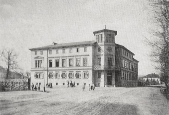 Black and white photo, at the right front corner a tower, classicistic building over three floors