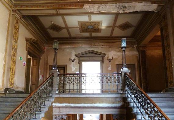 Staircase in the former state parliament building before renovation in 2011. Wallpaper and walls are worn and peeling.