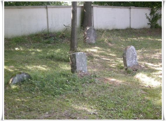 In the foreground single gravestones. Behind the white cemetery wall