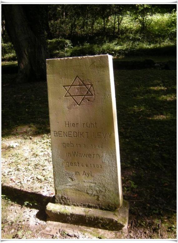 Single tombstone, large. Square. On a meadow.