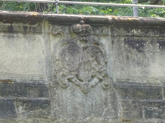 Detailansich einer alten Steinbrücke, zu sehen ist ein in den Stein gearbeitetes Wappen oder Wahrzeichen