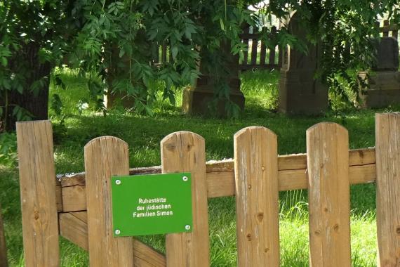 Wooden fence gate, behind it a cemetery