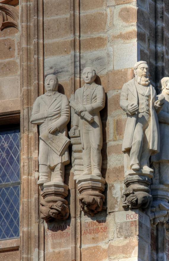 Three statues of men serving as decoration of a building.