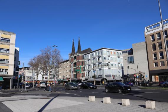 Foto einer modernen Straße mit mehreren Gebäuden und Autos im Hintergrund.