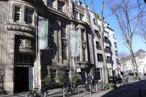 Photo of a large building. On the side of the building are two flags.