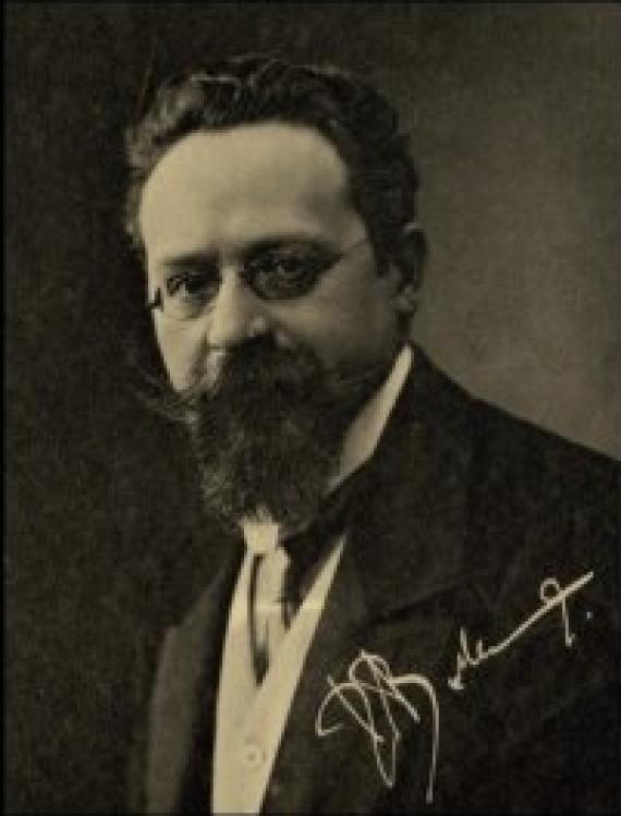 Old portrait photo of a man. He wears glasses and beard.