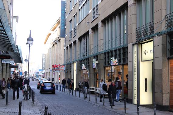 Small modern street with cars and stores.