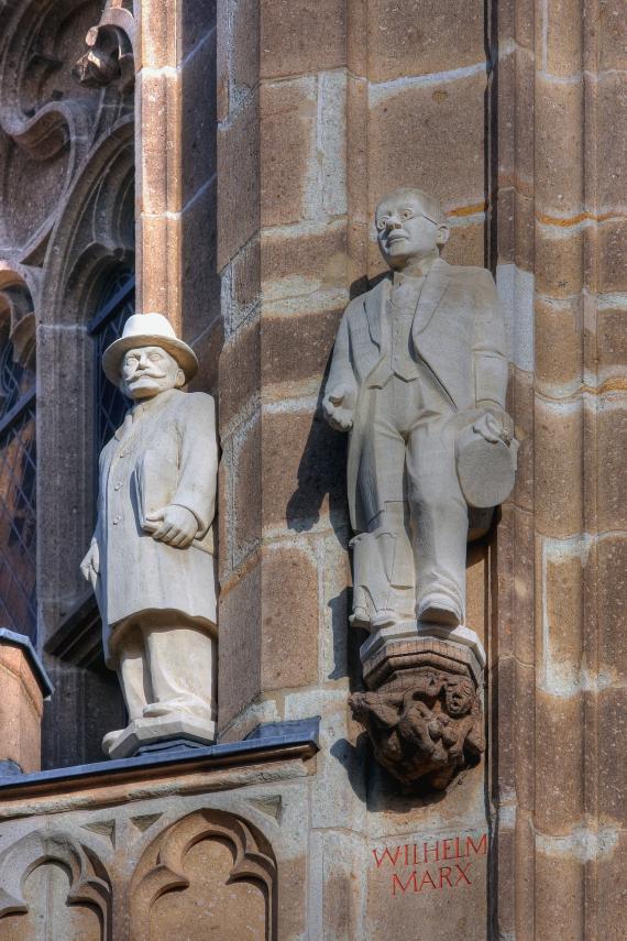Zwei Menschenstatuen an einem Gebäude.