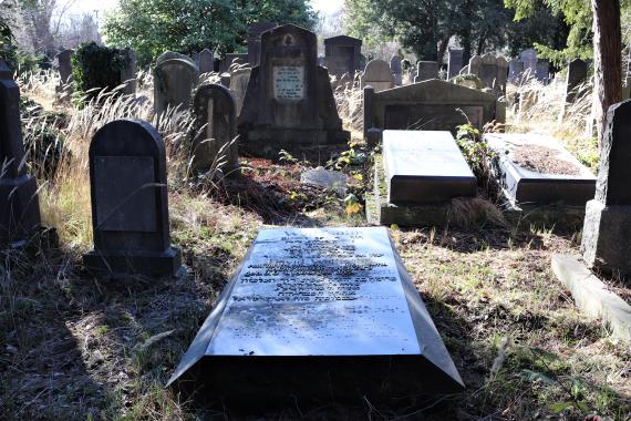 Photo of a cemetery. In the center of the picture is a large lying tombstone.