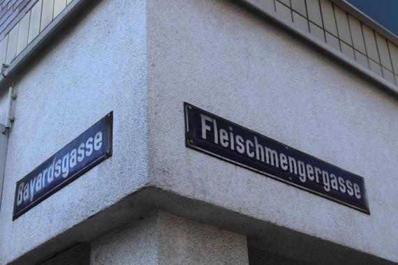 Two street signs attached to a house.