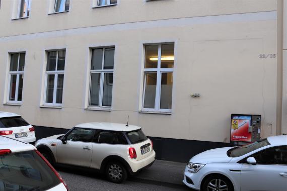 Lower floor of a residential building. Cars are parked in front of the building.