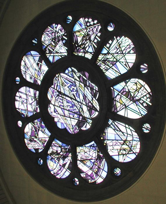 Photo of the rose window from the inside. Stained glass with patterns can be seen.