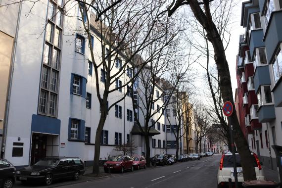 Foto einer heutigen Straße mit Wohngebäuden und Autos.