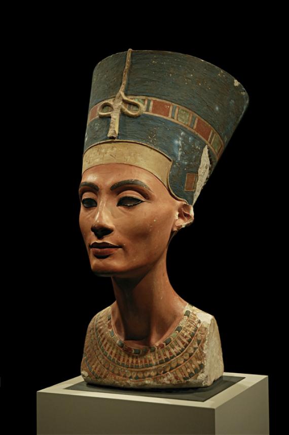 Bust of Queen Nefertiti. She wears a blue helmet crown with a golden headband and a multicolored collar.