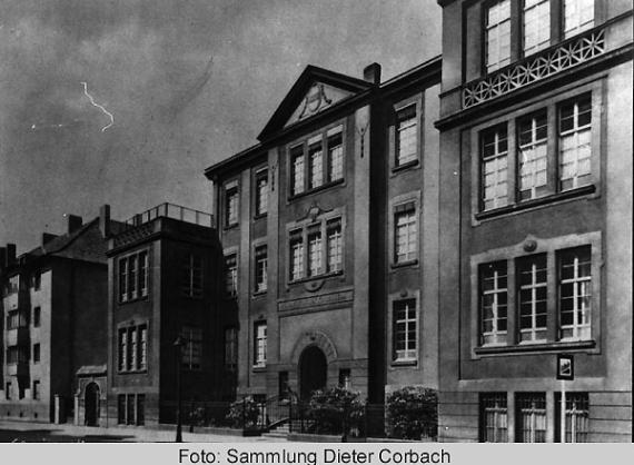 Old black and white picture of a street. Large building can be seen.