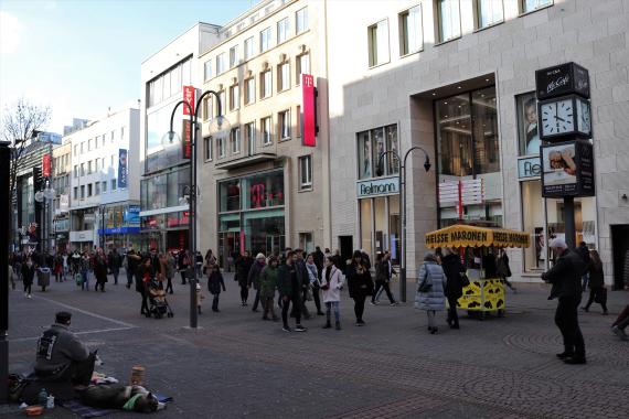 Foto einer Kaufstraße mit vielen Menschen und Geschäften.