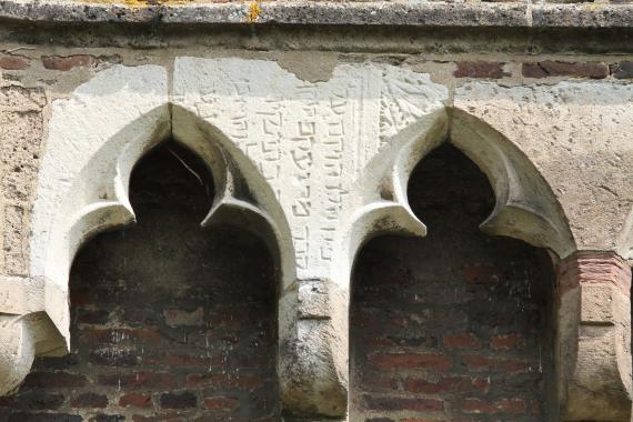 Arched frieze with central tombstone.