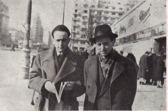 b/w photo, two men in coats, the right one with hat