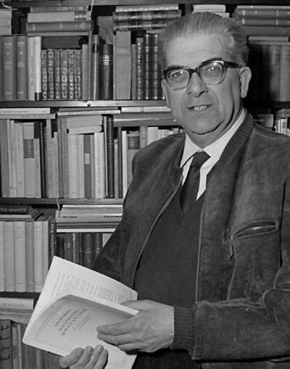 b/w photo, older gentleman in suit holds magazine in hand